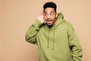 Young curious nosy man of African American ethnicity wear green hoodie casual clothes try to hear...