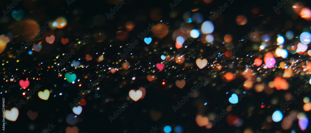 Poster Light bokeh texture with heart shapes creating a romantic atmosphere on black background