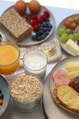 Assortment of various breakfast foods and drinks on the white table. Selective focus.