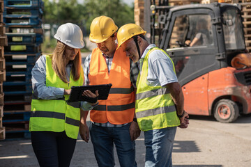 Wooden industry workers walk with their supervisor on the factory yard, checking numbers and quality of products. They discuss production details and ensure standards are met.	

