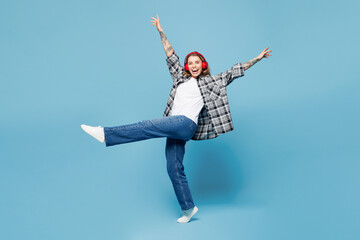 Full body young woman she wears checkered grey shirt casual clothes listen to music in headphones...