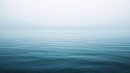 Obraz premium Serene foggy seascape with calm waters reflecting soft light, ideal for tranquil backgrounds