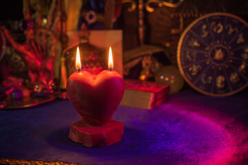 Love magic, spells and attracting relationship in life. Red heart candle burning on a table