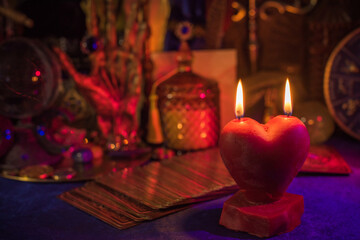 Love magic, spells and attracting relationship in life. Red heart candle burning on a table