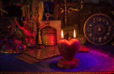 Love magic, spells and attracting relationship in life. Red heart candle burning on a table