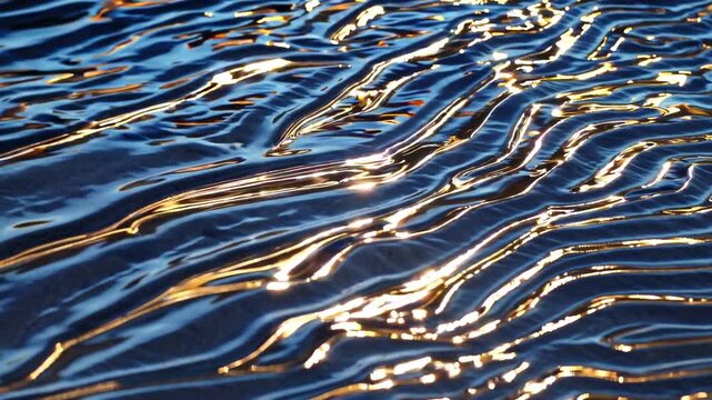 Golden sunlight reflections on the surface of blue water creating dynamic ripples and patterns with shimmering light and a captivating abstract texture