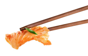 Chopsticks holding kimchi cabbage on white background. Hot fermented napa cabbage.