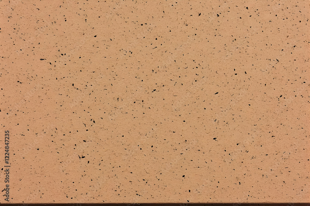 Poster close-up of a textured tan surface with dark specks shows detail and evenly distributed imperfection