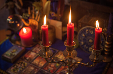 Esoteric concept, some witch stuff on altar. Candle burning on a table