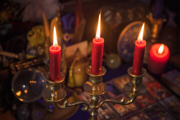 Esoteric concept, some witch stuff on altar. Candle burning on a table