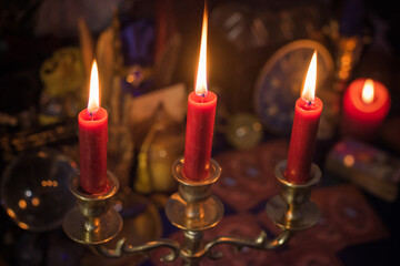 Esoteric concept, some witch stuff on altar. Candle burning on a table