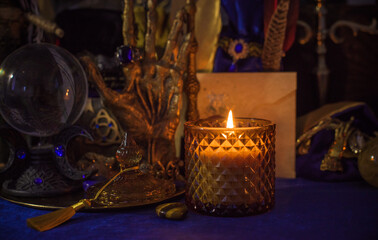 Esoteric concept, some witch stuff on altar. Candle burning on a table