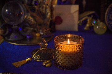 Esoteric concept, some witch stuff on altar. Candle burning on a table