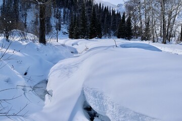 A frozen stream in a winter forest in the mountains