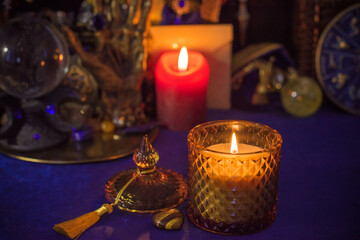 Esoteric concept, some witch stuff on altar. Candle burning on a table