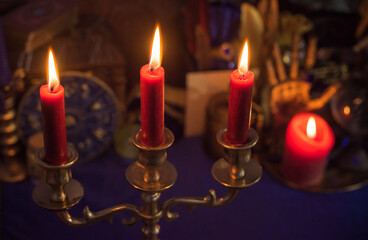 Esoteric concept, some witch stuff on altar. Candle burning on a table