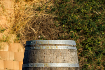 Obraz premium Pedestal oak wooden barrel with metal rims for aging wine or other alcoholic beverages at vinery yard, outdoor. Winery equipment.