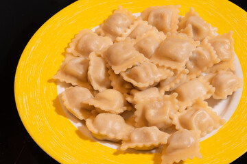 Homemade dumplings on a white plate with a yellow rim.