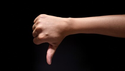 human hand in a thumbs-down gesture, expressing disapproval, rejection, or dissatisfaction, with fingers curled and thumb pointing downward, captured against a dark background with dramatic lighting f
