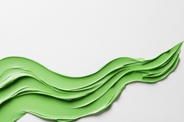 Fototapeta premium Green paste forming a wavy pattern on a white background, evoking nature and freshness