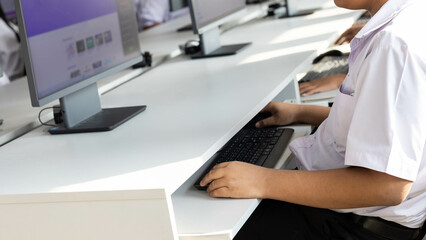 Students in uniforms are studying computer using a mouse and keyboard.