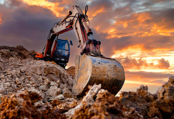 Excavator during earthmoving work at open-pit mining on sunset background. Loader machine with bucket in sand quarry. Backhoe digging th ground for the foundation and for laying sewer pipes © MaxSafaniuk