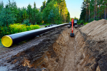 Excavator digging trench in ground for laying pipeline of natural gas. Building of transit...