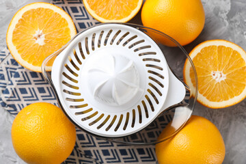 Plastic juicer and oranges on grey table, top view