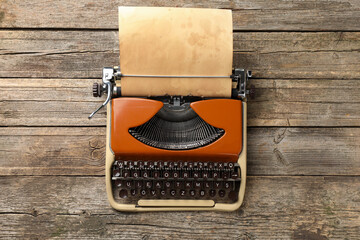 Vintage typewriter with sheet of parchment paper on wooden table, top view