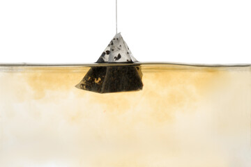 Putting tea bag into glass cup on white background, closeup