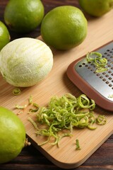 Lime zest, grater and fresh fruits on wooden table, closeup