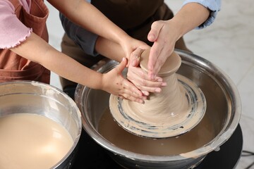 Hobby and craft. Mother with her daughter making pottery indoors, closeup