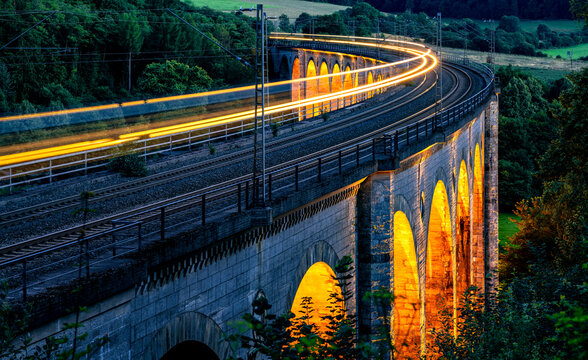 The Beke Viaduct near Altenbeken is a 482 m long arched bridge structure that spans the Beketal valley on the double-track Hamm-Warburg railroad line. Panoramic view at evening dusk with passing train