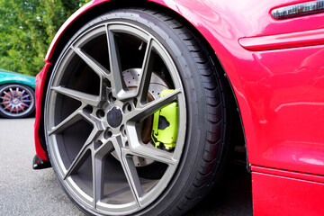 Alloy wheel with calipers and racing brakes of the sport car. Racing brake disc and low profile tyres. Race car test driving. Lower-profile tires of drag and drift cars. High-performance sports cars.