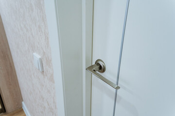 This is a detailed closeup shot of a door handle located on a pristine white door, showcasing its design and functionality. Its an important part of household hardware and security