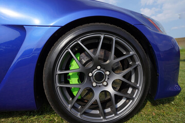 Alloy wheel with calipers and racing brakes of the sport car. Racing brake disc and low profile tyres. Race car test driving. Lower-profile tires of drag and drift cars. High-performance sports cars.