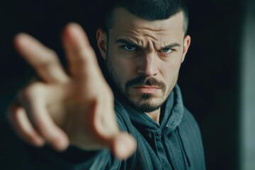 Fototapeta premium Male model poses dramatically with an intense expression and outstretched hand in a dark environment