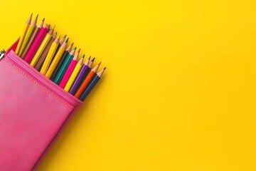 Fototapeta premium Colorful art supplies in a pink pencil case against a yellow background.