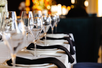 aesthetically decorated table in a restaurant with napkins, glasses, flowers and beautiful dishes against the background of a panoramic window with the setting sun