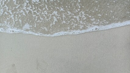 Close-up view of gentle waves lapping against the sandy shore, perfect for beach and relaxation themes