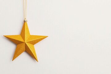 Obraz premium Golden star ornament hanging on a plain background, perfect for Christmas decoration and festive themes, symbolizing celebration and joy