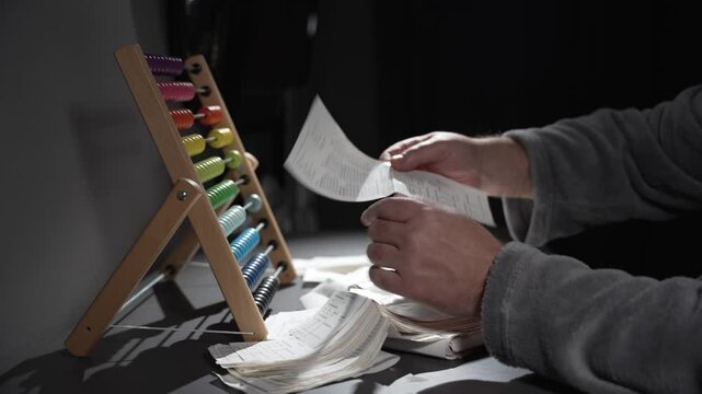 A person is using a colorful abacus to count. The abacus has a variety of colored beads, and the person is focused on the task at hand