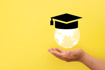 Global Education concept.,Hand holding globe with education cap over yellow background idea for International Learning, Global Knowledge,Cultural Exchange,Online Education.