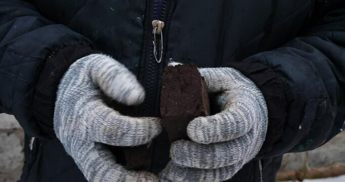 Peat briquettes for kindling a stove A worker wearing gloves carefully examines peat briquettes assessing their suitability for burning in a stove emphasizing the importance of fuel in cold climates.