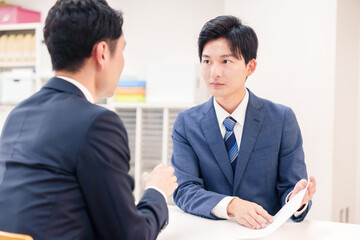窓口で来客の対応をするビジネスマン