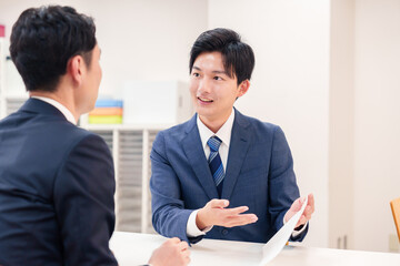 窓口で来客の対応をするビジネスマン