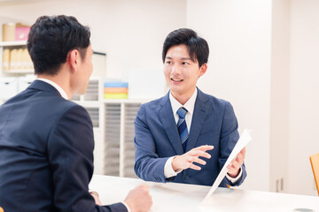 窓口で来客の対応をするビジネスマン