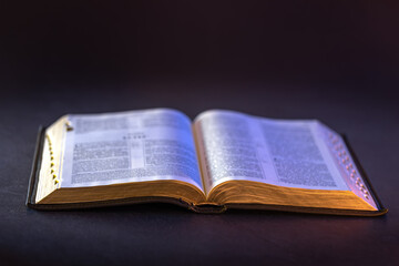 Fototapeta premium Open Holy Bible on the table. Religion concept. Bible on black background.