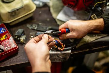 Car mechanic electrician working on batteries and electrical wiring