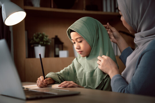 Muslim mother teaching her daughter the Quran and Arabic language at home, embracing faith, family values, and cultural traditions in a warm and loving living room setting
